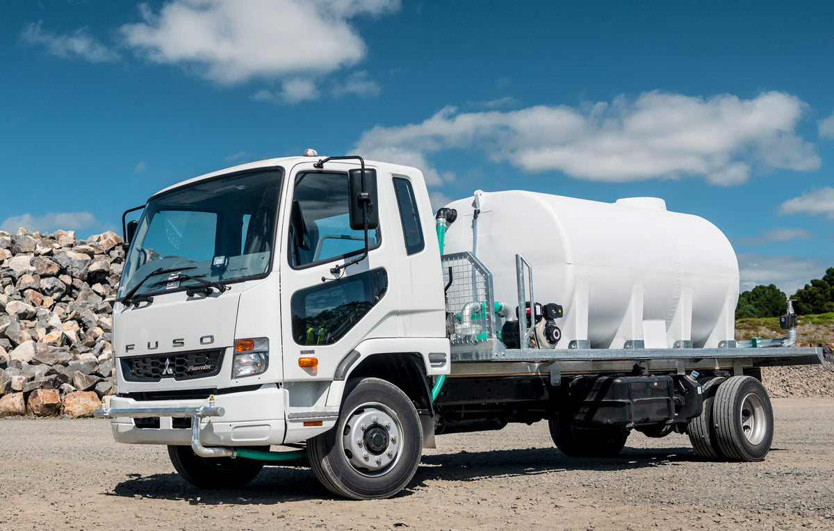 A Promax slip-on dust suppression unit on a Fuso truck parked in a quarry yard beside a rock pile
